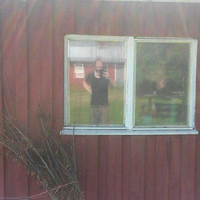 Tekotaiteellinen peiliselfie vanhan navetan ikkunasta